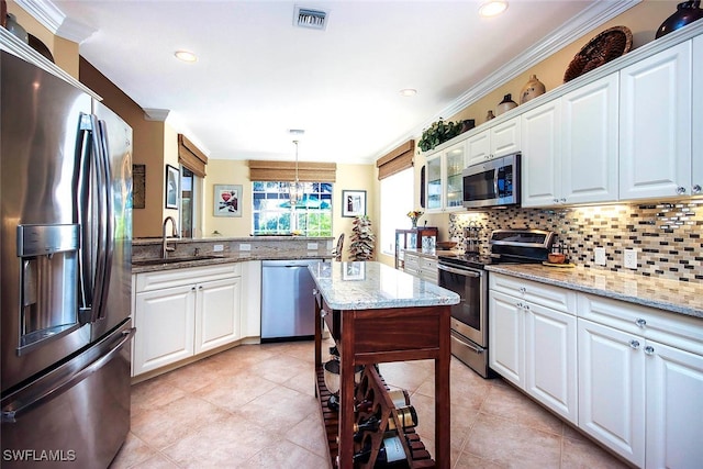 kitchen featuring appliances with stainless steel finishes, ornamental molding, sink, pendant lighting, and white cabinets