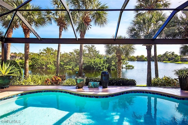 view of pool featuring glass enclosure and a water view