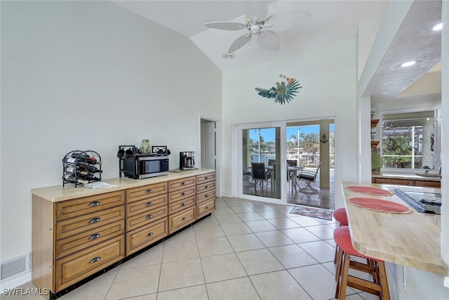 interior space featuring access to exterior, light tile patterned floors, multiple windows, and ceiling fan