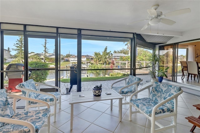 sunroom / solarium featuring ceiling fan and a water view