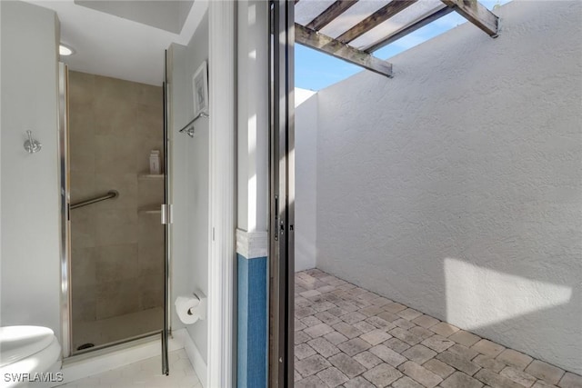 bathroom with a shower with door and toilet