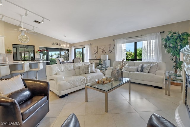 tiled living room featuring ceiling fan with notable chandelier, rail lighting, and lofted ceiling