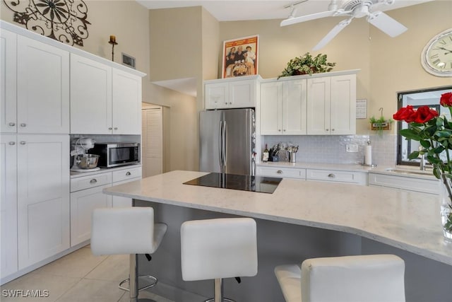 kitchen with a breakfast bar, white cabinets, tasteful backsplash, light stone counters, and stainless steel appliances