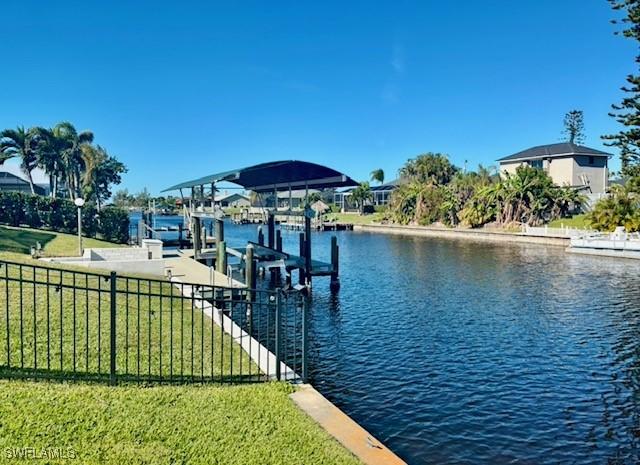 view of dock with a lawn and a water view