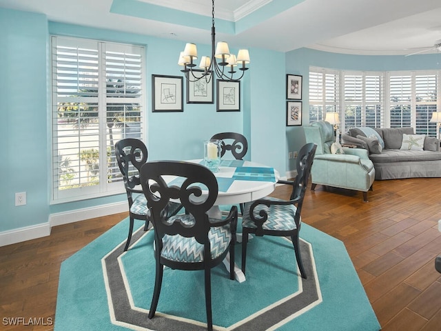 dining room featuring a raised ceiling, ceiling fan with notable chandelier, dark hardwood / wood-style flooring, and ornamental molding