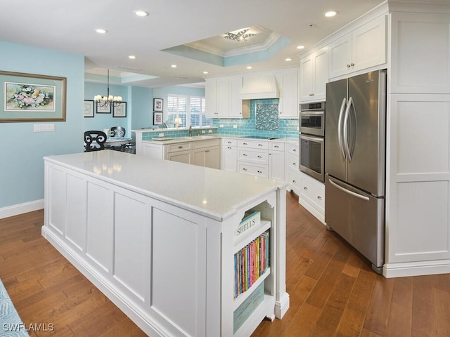 kitchen with pendant lighting, kitchen peninsula, appliances with stainless steel finishes, dark hardwood / wood-style flooring, and white cabinetry