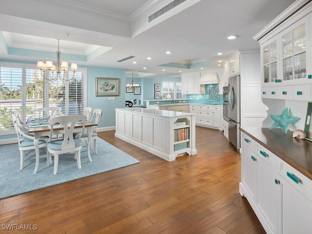 dining room featuring a raised ceiling, an inviting chandelier, dark wood-type flooring, and crown molding