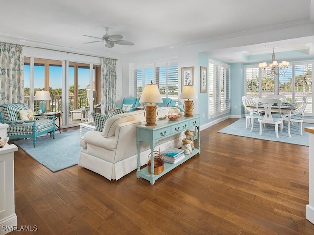 living room featuring ceiling fan with notable chandelier, crown molding, and dark wood-type flooring