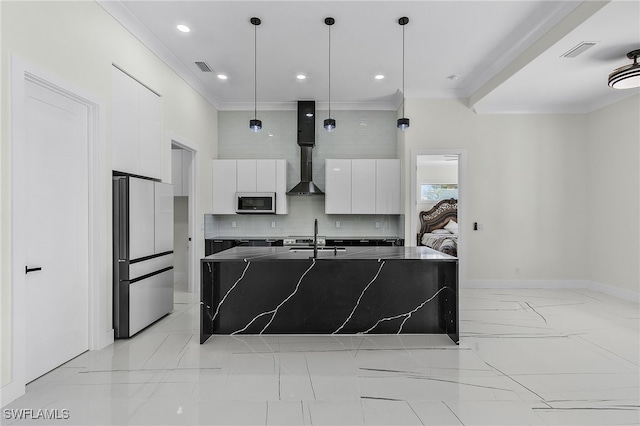 kitchen with white cabinetry, wall chimney exhaust hood, stainless steel appliances, an island with sink, and decorative light fixtures