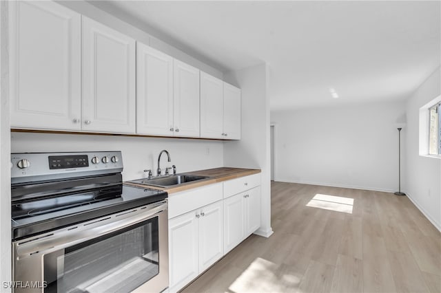 kitchen featuring electric range, white cabinetry, light wood-type flooring, and sink