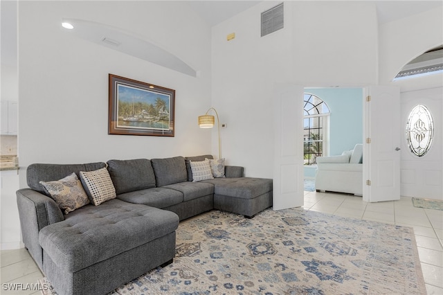 living room featuring a towering ceiling and light tile patterned floors