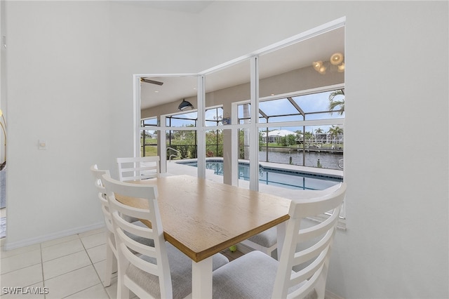 tiled dining room with a water view and ceiling fan