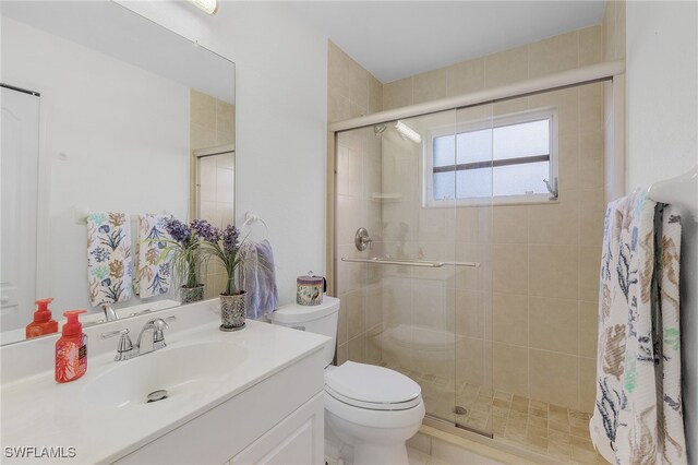 bathroom with toilet, an enclosed shower, and vanity