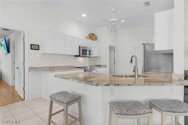 2819 SW 37th Ter, Cape Coral, FL 33914 - kitchen with appliances with stainless steel finishes, a sink, light stone counters, a peninsula, and white cabinets