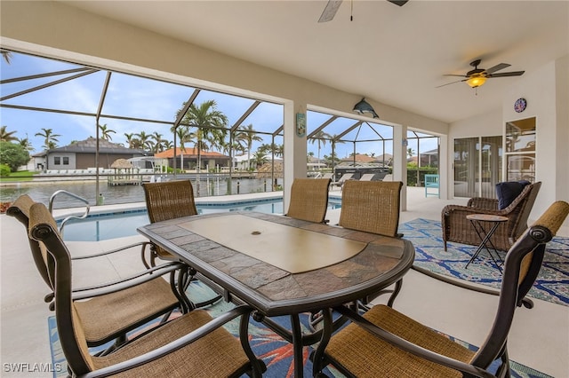 sunroom with ceiling fan, a water view, lofted ceiling, and a pool