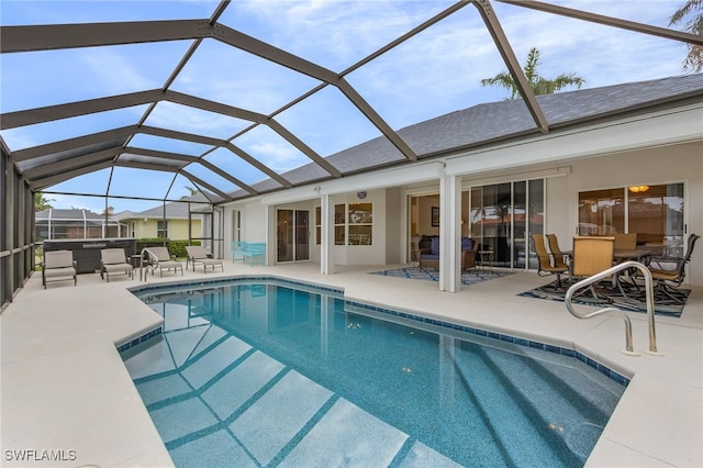 view of pool featuring glass enclosure, a patio area, and an outdoor living space