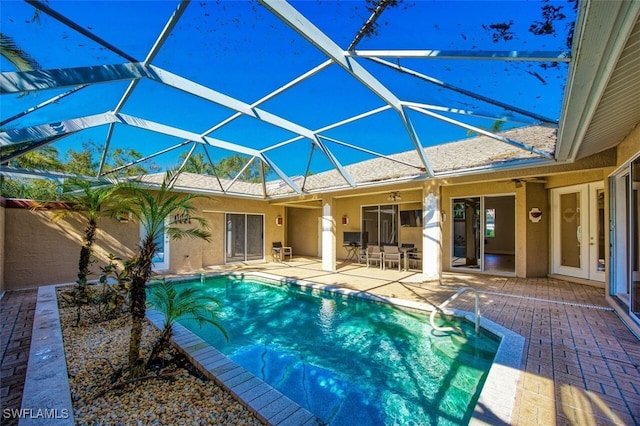 view of swimming pool with ceiling fan, a lanai, and a patio