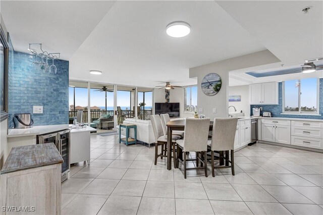 dining room featuring light tile patterned floors, wine cooler, ceiling fan, and sink