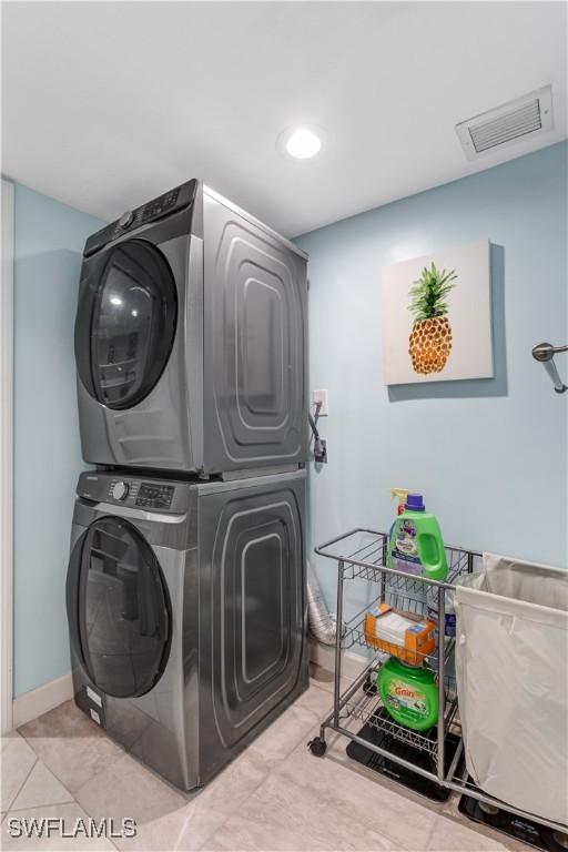 washroom with light tile patterned floors and stacked washer / drying machine