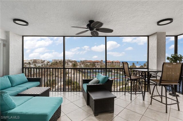 sunroom / solarium featuring ceiling fan and a water view