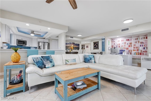 living room with a tray ceiling and light tile patterned flooring