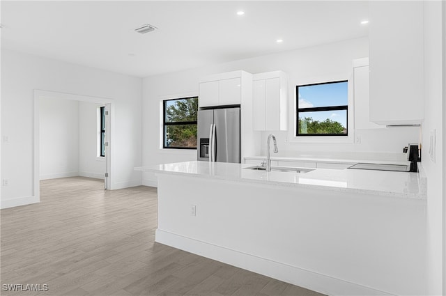 kitchen with white cabinets, stove, stainless steel fridge with ice dispenser, and kitchen peninsula