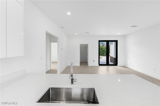 kitchen with white cabinetry, sink, and light hardwood / wood-style flooring