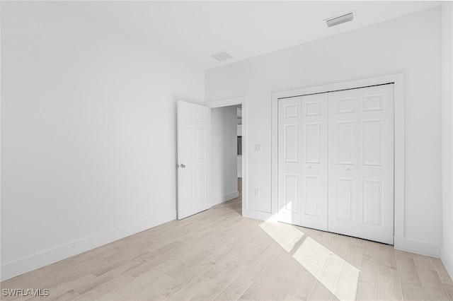 unfurnished bedroom with a closet and light hardwood / wood-style floors