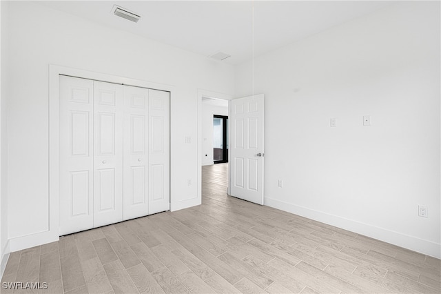 unfurnished bedroom with light hardwood / wood-style floors and a closet