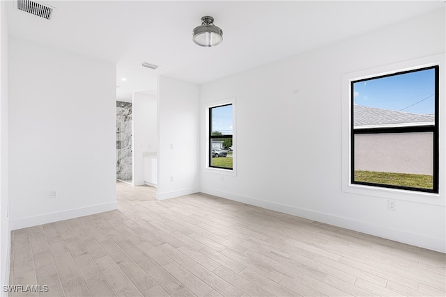 spare room featuring a healthy amount of sunlight and light hardwood / wood-style flooring