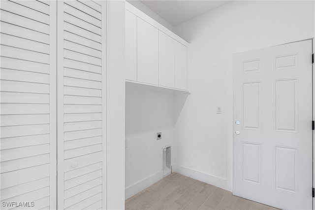 washroom with hookup for an electric dryer, light hardwood / wood-style floors, and cabinets