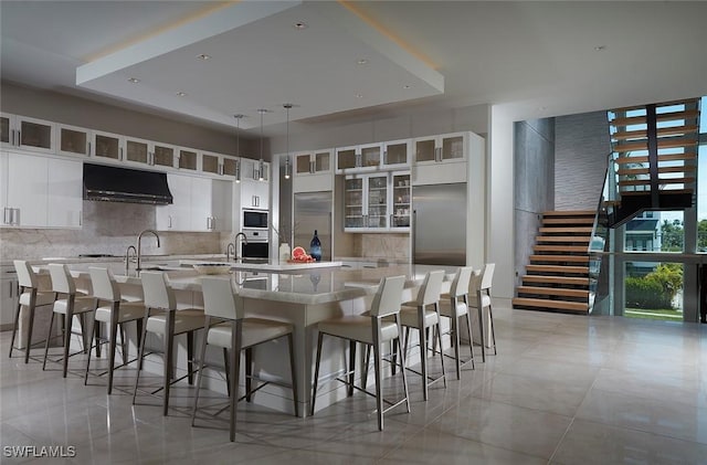 27804 Hickory Blvd, Bonita Springs, FL 34134 - kitchen featuring under cabinet range hood, a spacious island, tasteful backsplash, and light tile patterned flooring