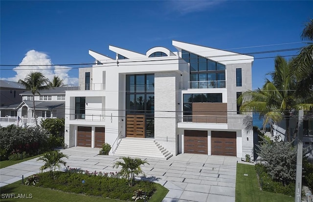 27804 Hickory Blvd, Bonita Springs, FL 34134 - modern home with driveway, an attached garage, stucco siding, and a balcony