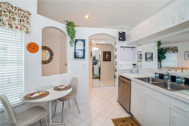 kitchen with dishwasher, sink, light tile patterned floors, plenty of natural light, and white cabinets