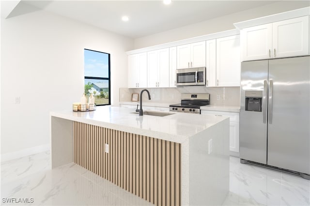 kitchen with white cabinetry, sink, appliances with stainless steel finishes, and an island with sink