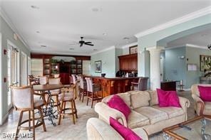 living room with ornate columns, ceiling fan, and ornamental molding