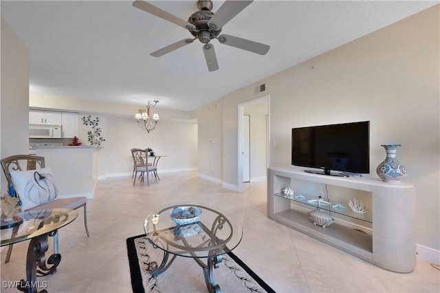 tiled living room featuring ceiling fan with notable chandelier and a textured ceiling