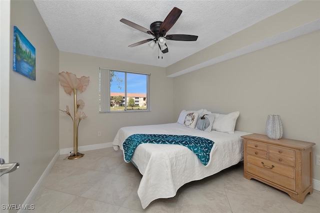 bedroom featuring ceiling fan, light tile patterned floors, and a textured ceiling