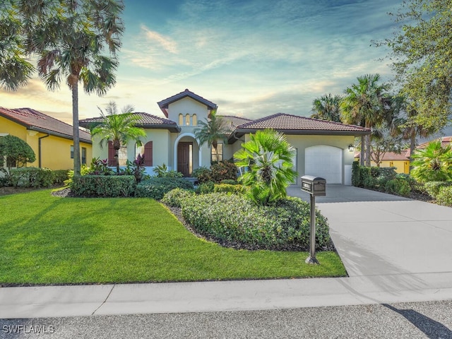 mediterranean / spanish-style home featuring a yard and a garage