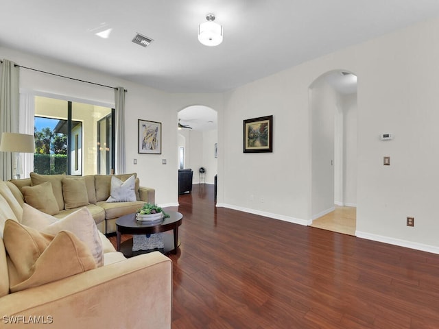 living room with ceiling fan and dark wood-type flooring