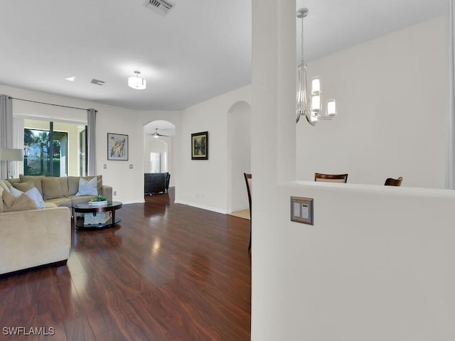 living room featuring ceiling fan with notable chandelier and dark hardwood / wood-style floors