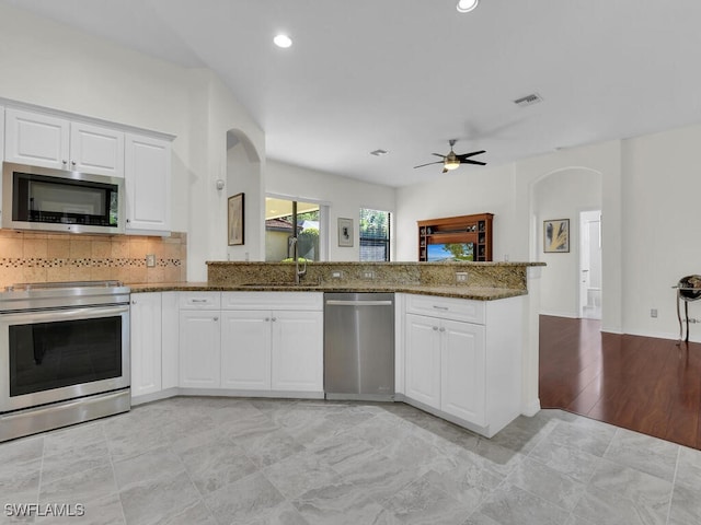 kitchen with sink, ceiling fan, dark stone countertops, appliances with stainless steel finishes, and white cabinetry