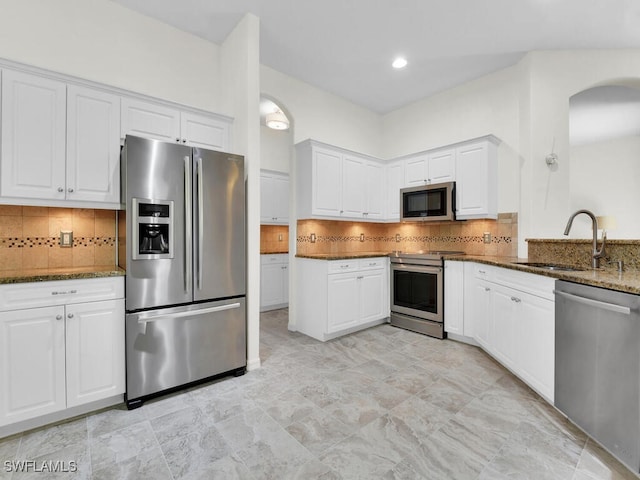 kitchen featuring white cabinets, appliances with stainless steel finishes, sink, and dark stone countertops