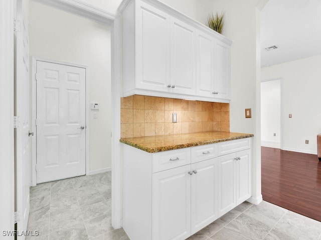 kitchen featuring backsplash, dark stone countertops, white cabinetry, and light hardwood / wood-style floors