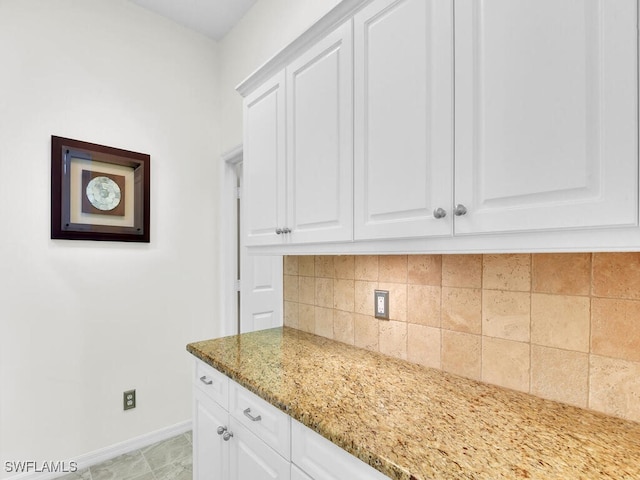 kitchen with light tile patterned floors, tasteful backsplash, white cabinetry, and light stone counters