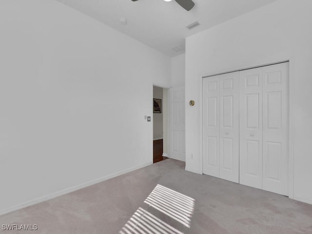 unfurnished bedroom featuring light carpet, a closet, and ceiling fan