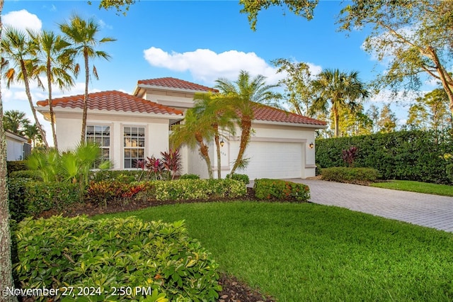 mediterranean / spanish-style home with a garage and a front lawn