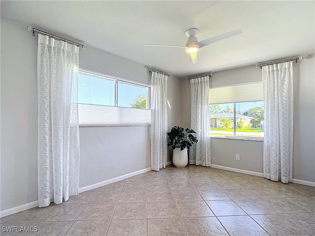 tiled empty room featuring ceiling fan and a healthy amount of sunlight