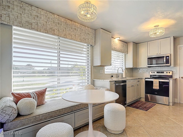 kitchen with sink, decorative backsplash, light tile patterned flooring, white cabinetry, and stainless steel appliances