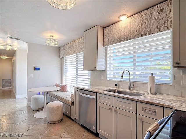 kitchen with light stone countertops, tasteful backsplash, stainless steel dishwasher, and sink